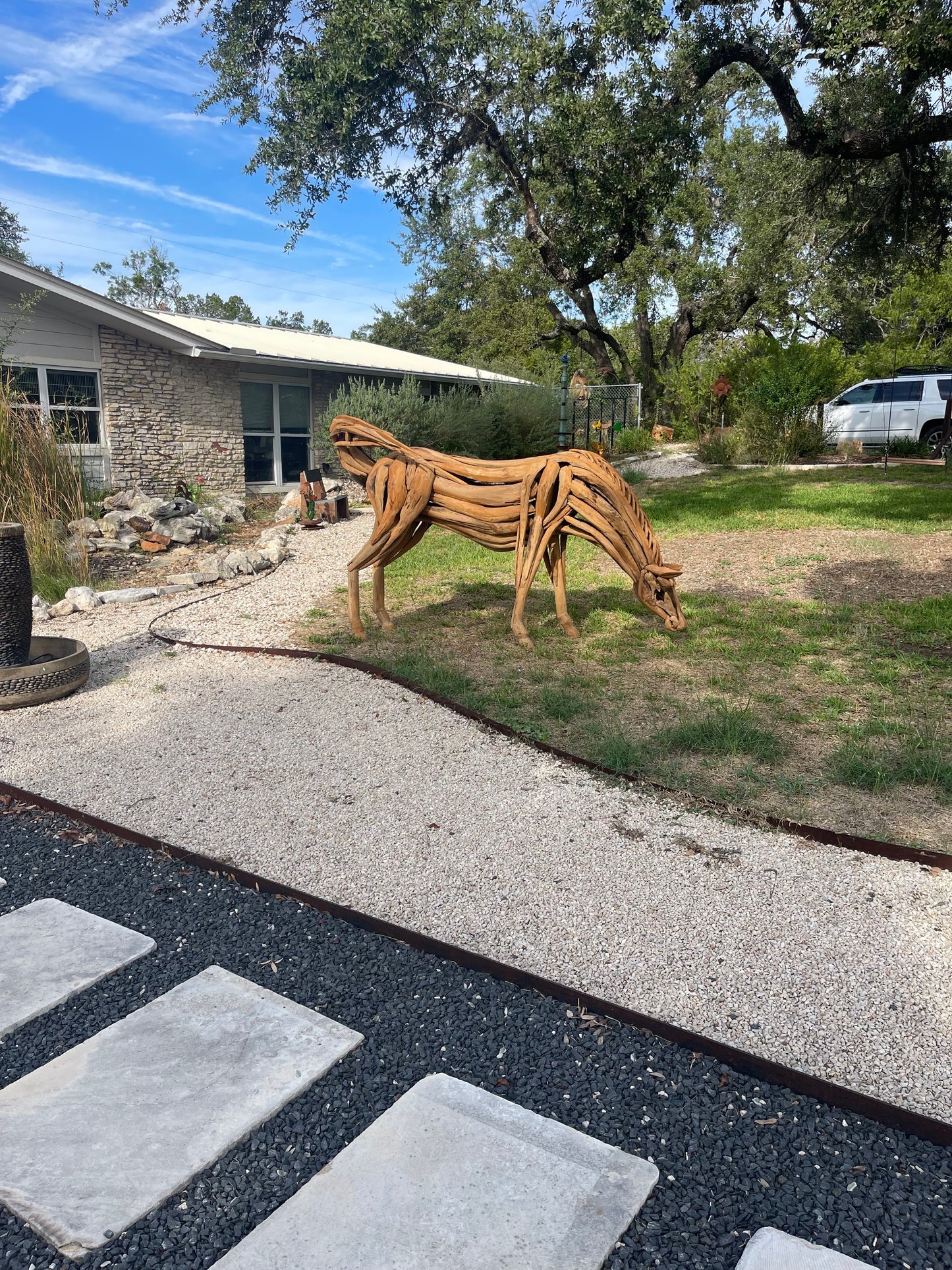 Life sized sculpture of a grazing horse swatting flies with its tail