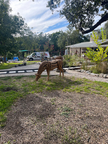 Life sized sculpture of a grazing horse swatting flies with its tail
