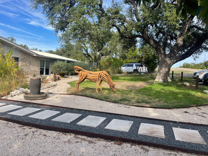 Life sized sculpture of a grazing horse swatting flies with its tail
